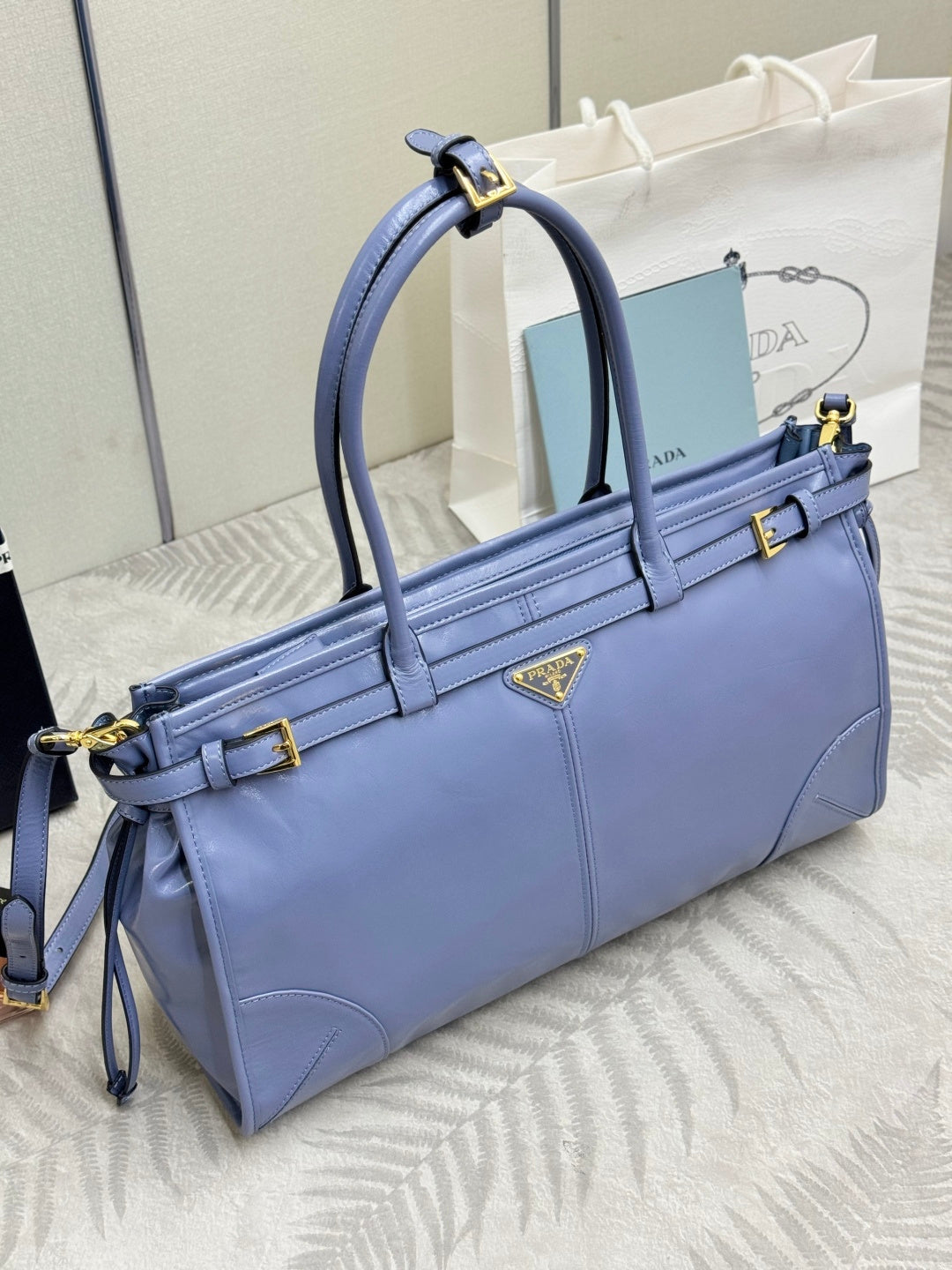 Light blue Prada handbag with top handles and adjustable shoulder strap, gold details