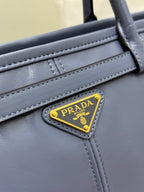 Close-up of Prada logo plaque on light blue leather handbag with stitched trim