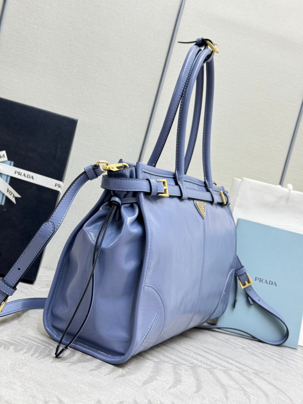 Light blue Prada handbag with drawstring-style top, shoulder strap, and gold hardware