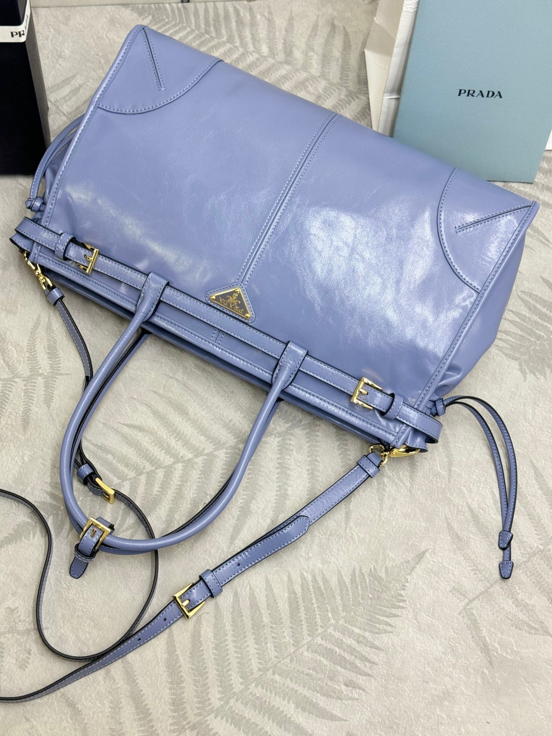 Light blue Prada leather shoulder bag with gold buckle straps and crossbody strap