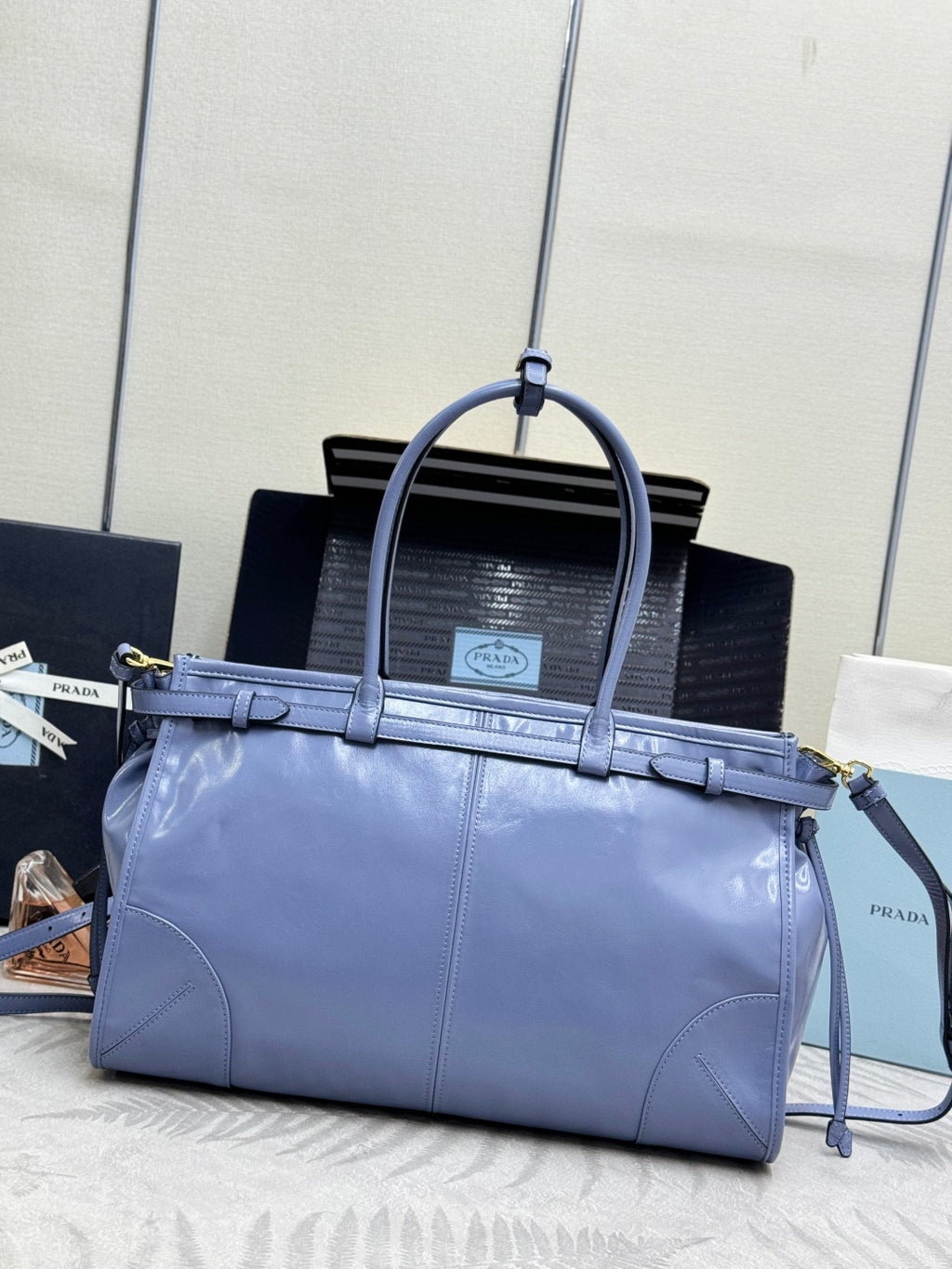 Light blue Prada handbag with top handles, front strap, and gold hardware