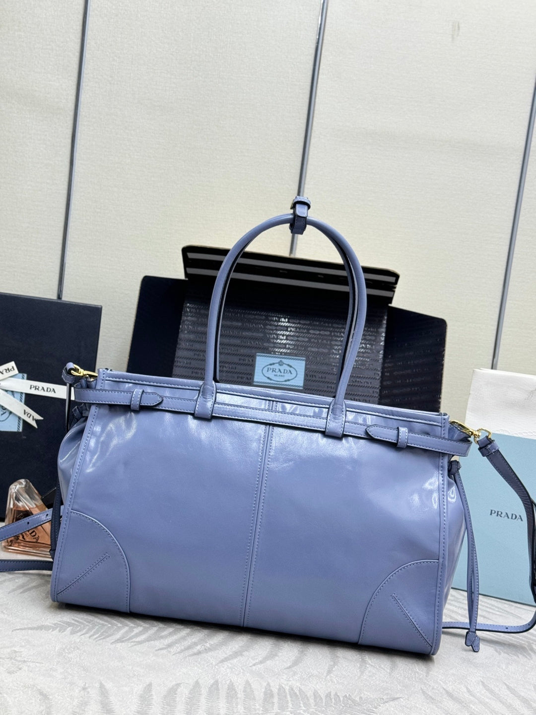 Light blue Prada handbag with top handles, front strap, and gold hardware