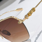 Chrome metal sunglasses close-up: gold temple detail with brown tinted lens