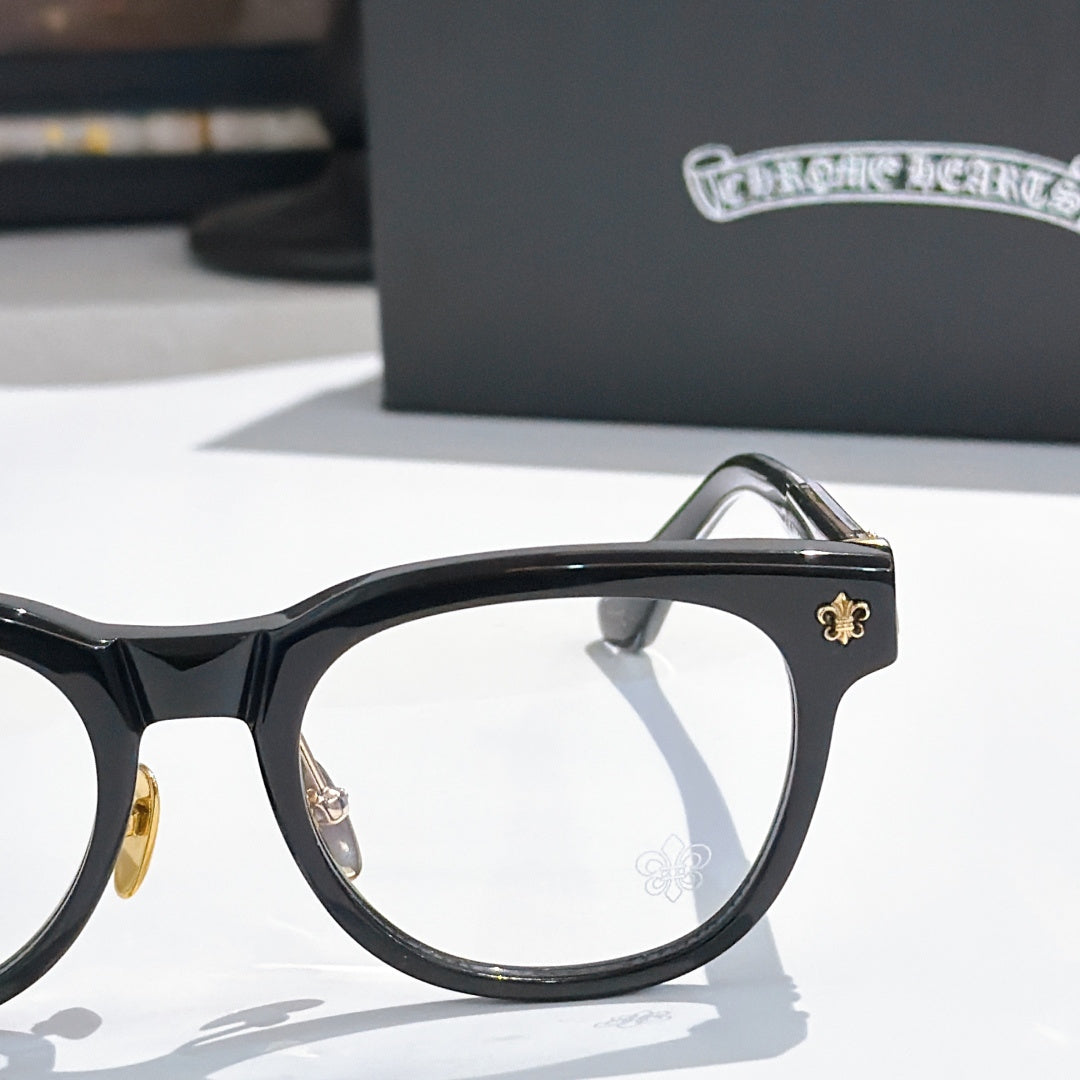 Black eyeglass frame with gold hinge detail and round-rectangle lens