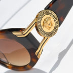 Close-up of tortoiseshell sunglasses with gold emblem temple detail