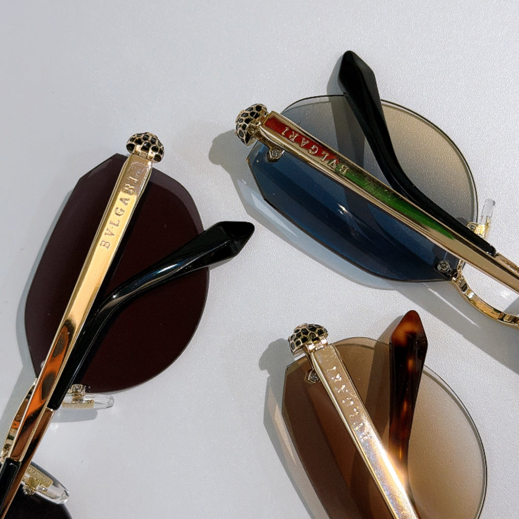 Assorted gold-tone sunglasses with tinted lenses, including dark and blue styles, logo temples