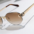 Close-up of gold-tone sunglasses with tan gradient lenses and tortoise temple tip