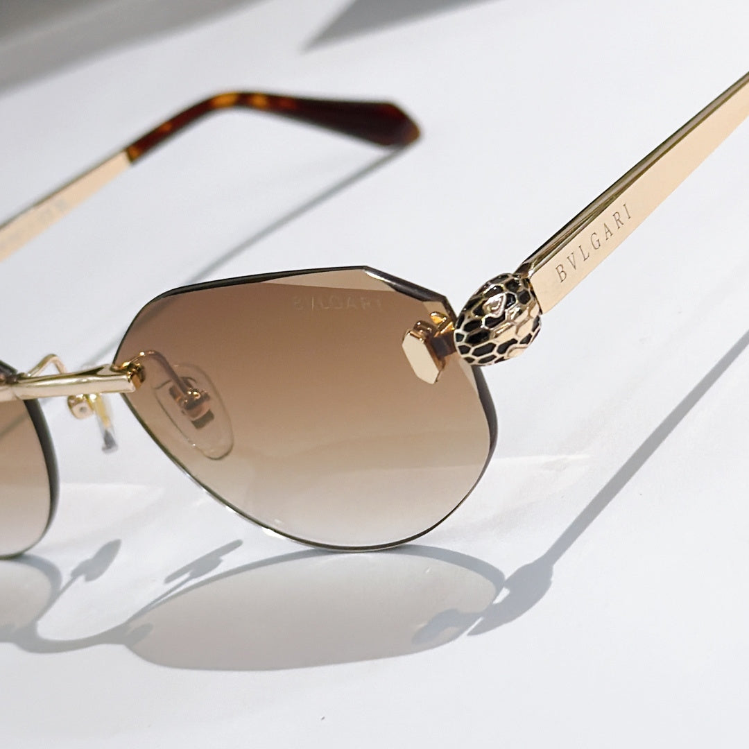 Close-up of gold-tone sunglasses with tan gradient lenses and tortoise temple tip