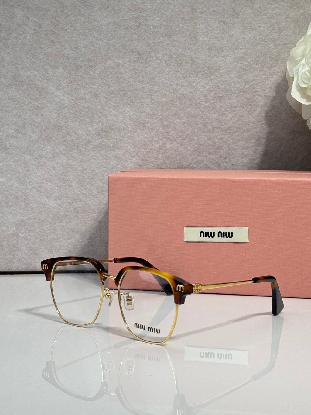 MiuMiu eyeglasses with black full-rim frame and clear lenses, gold-toned details
