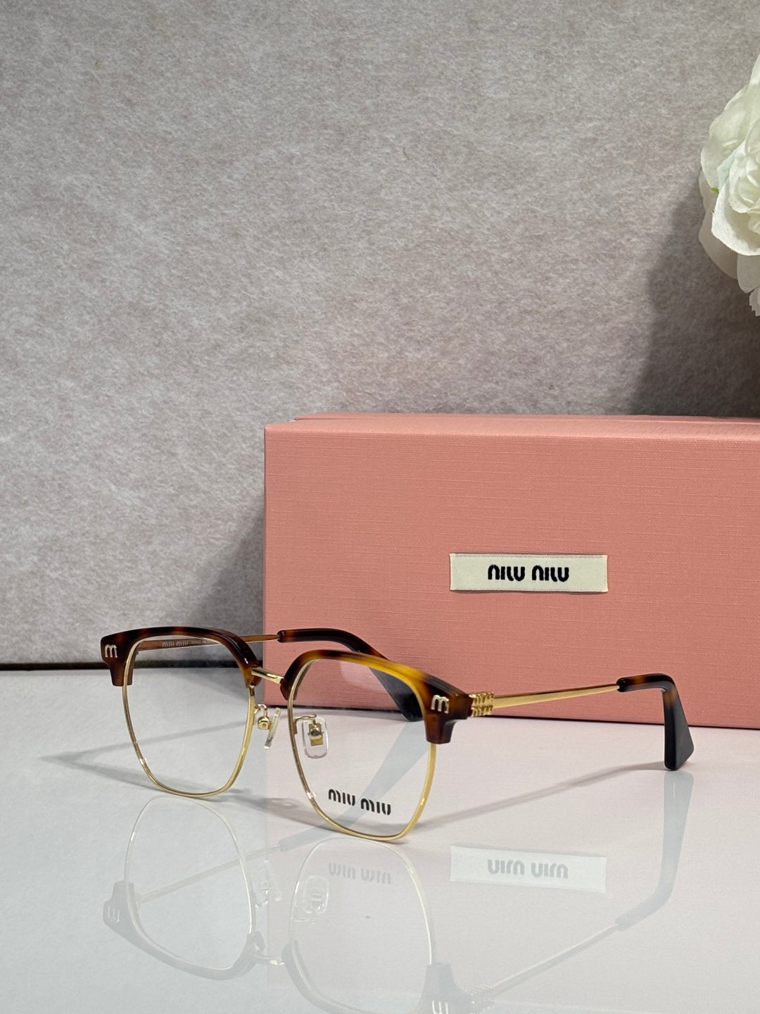 MiuMiu eyeglasses with black full-rim frame and clear lenses, gold-toned details