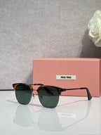 MiuMiu sunglasses with dark tortoiseshell frames, green-tinted lenses, and gold accents