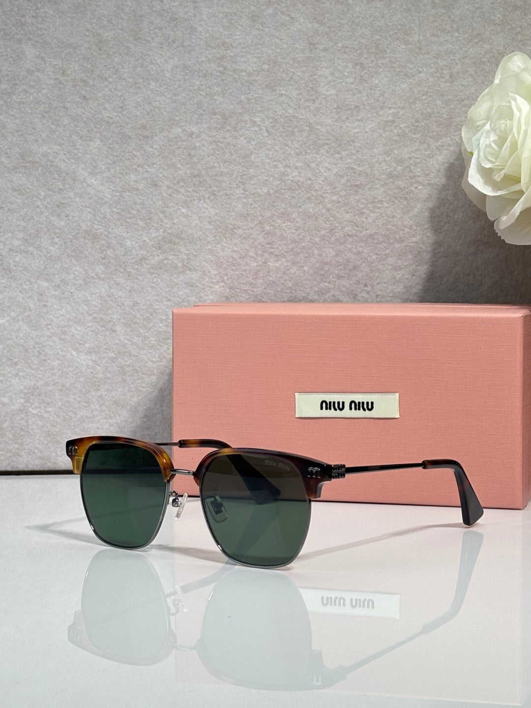 MiuMiu sunglasses with dark tortoiseshell frames, green-tinted lenses, and gold accents