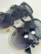MiuMiu sunglasses close-up showing gold-trim frames with dark lenses and “miu miu” markings