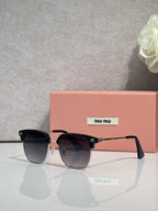 MiuMiu sunglasses with black oversized frames, dark lenses, and pink temple tips