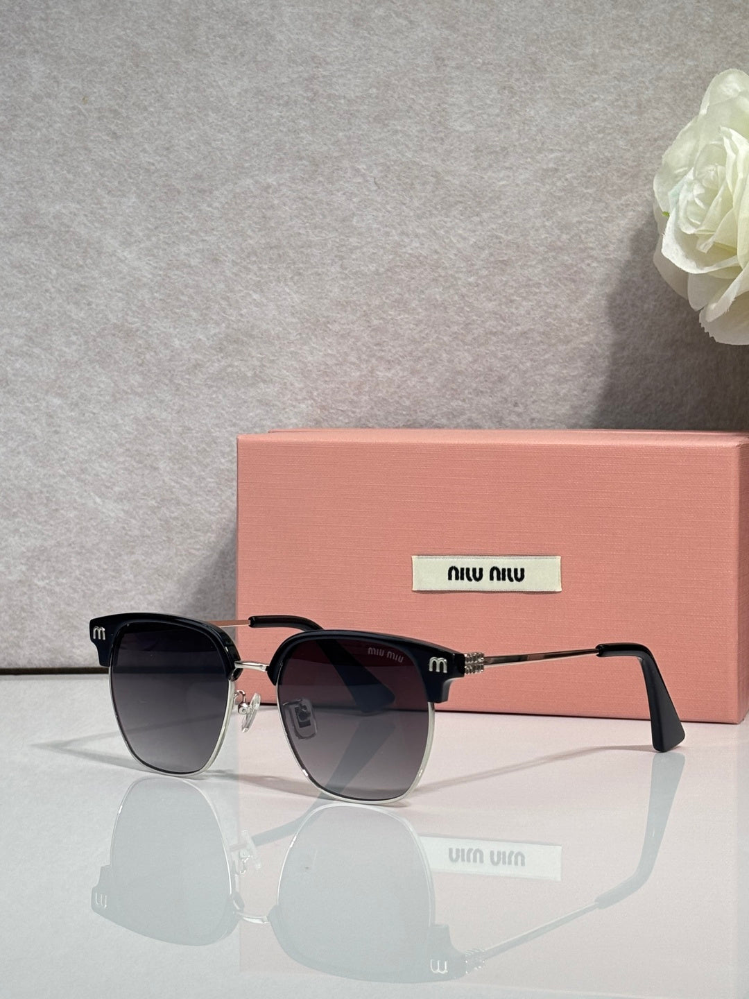 MiuMiu sunglasses with black oversized frames, dark lenses, and pink temple tips