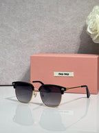 MiuMiu sunglasses with black frames, dark gradient lenses, and gold trim at the bridge