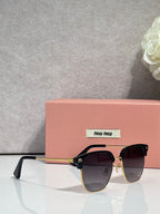 MiuMiu sunglasses with black frames, purple-tinted lenses, and gold emblem accents