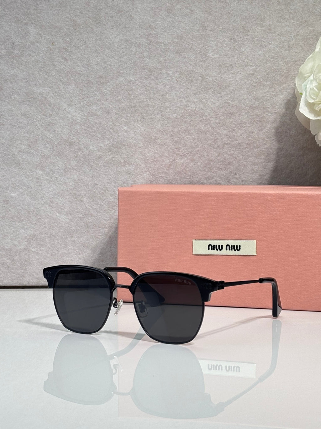 MiuMiu sunglasses with black oversized frames and dark lenses with metal rivet details