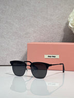 MiuMiu sunglasses with black oversized frames and dark lenses with metal rivet details