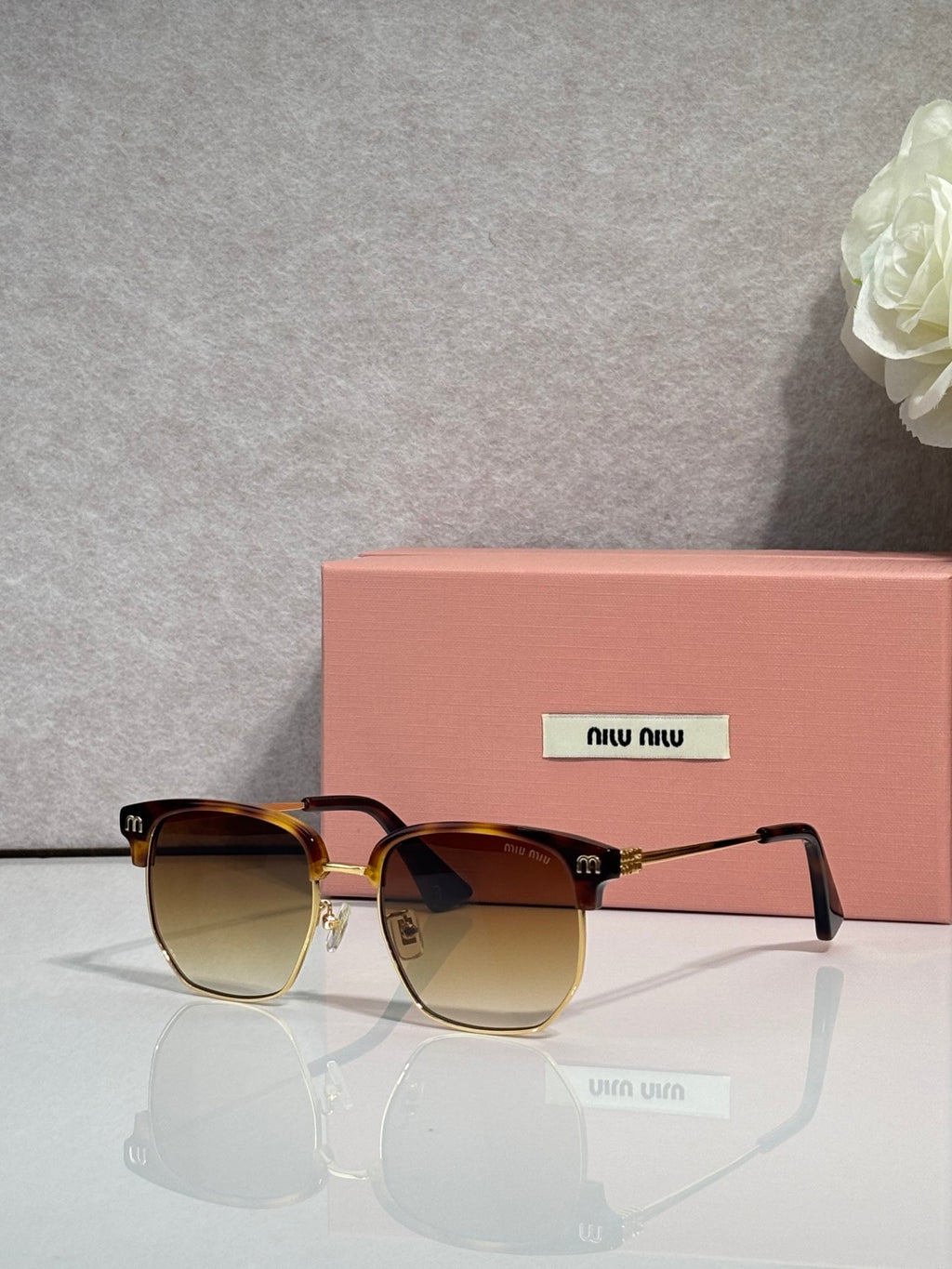 MiuMiu sunglasses with brown gradient frames, amber-tinted lenses, and gold detailing