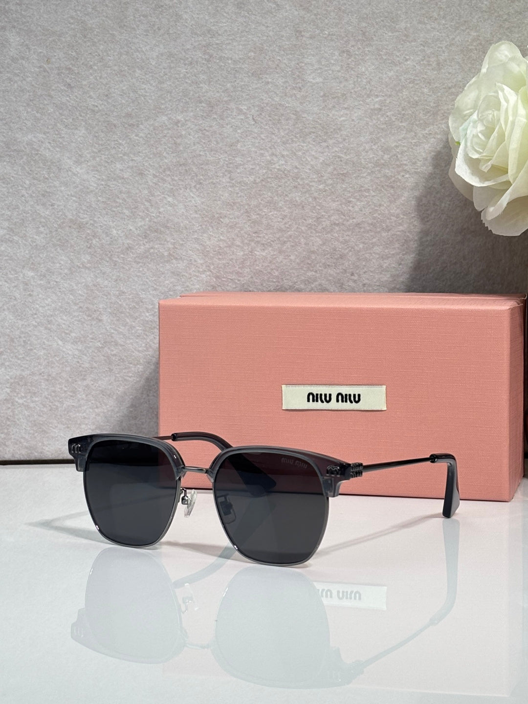 MiuMiu sunglasses with black frames, dark lenses, and gold bridge accents