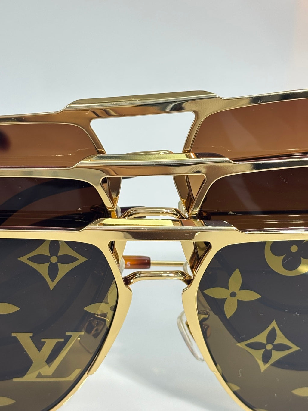 Louis Vuitton sunglasses close-up of gold frame and dark lenses with monogram pattern
