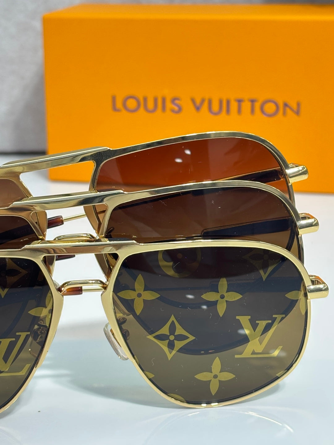 Louis Vuitton sunglasses close-up of dark lenses and gold frame with monogram design