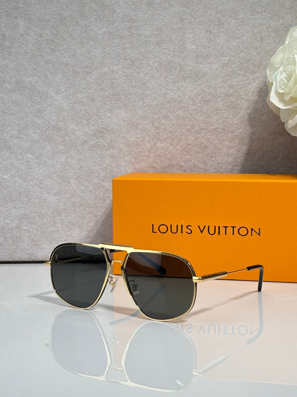 Louis Vuitton sunglasses with gold-tone frame, dark lenses, monogram design on temples