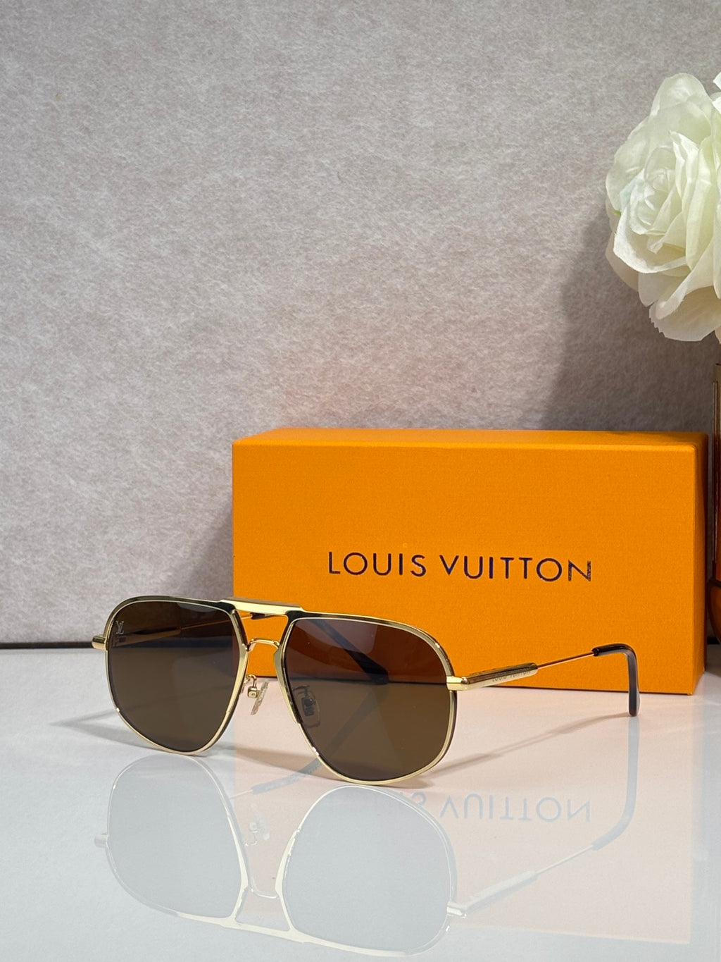 Louis Vuitton sunglasses with gold-tone frame, dark lenses, monogram pattern on sides