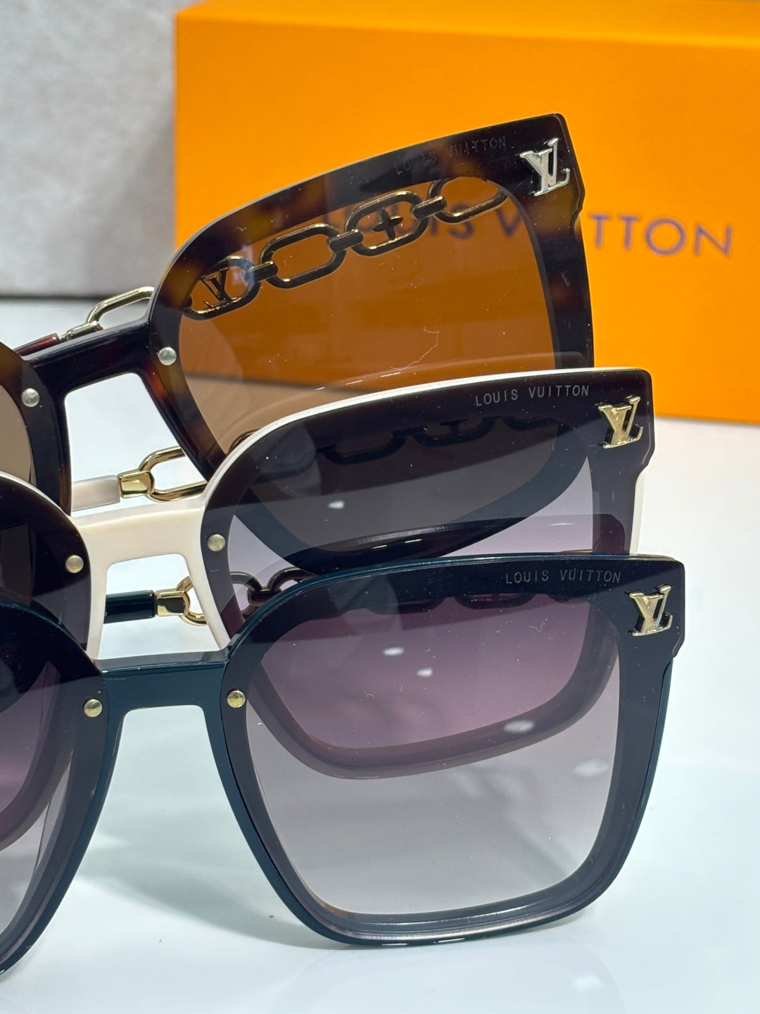 Louis Vuitton sunglasses close-up with dark lenses and gold chain across the top bar