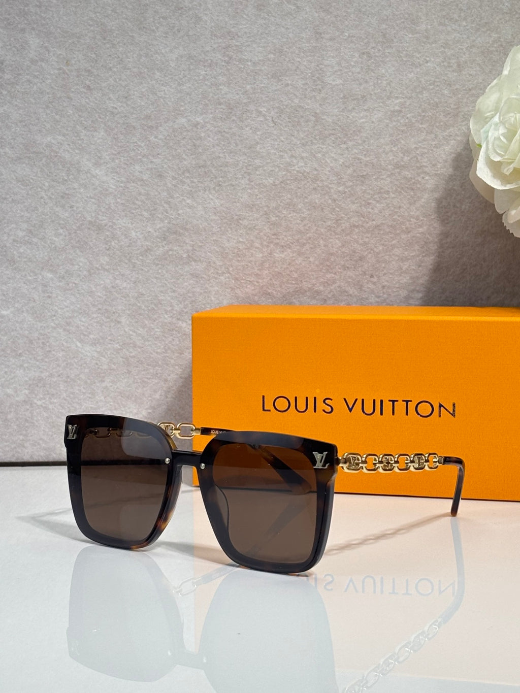 Louis Vuitton sunglasses with dark tortoiseshell frames and gold chain detail