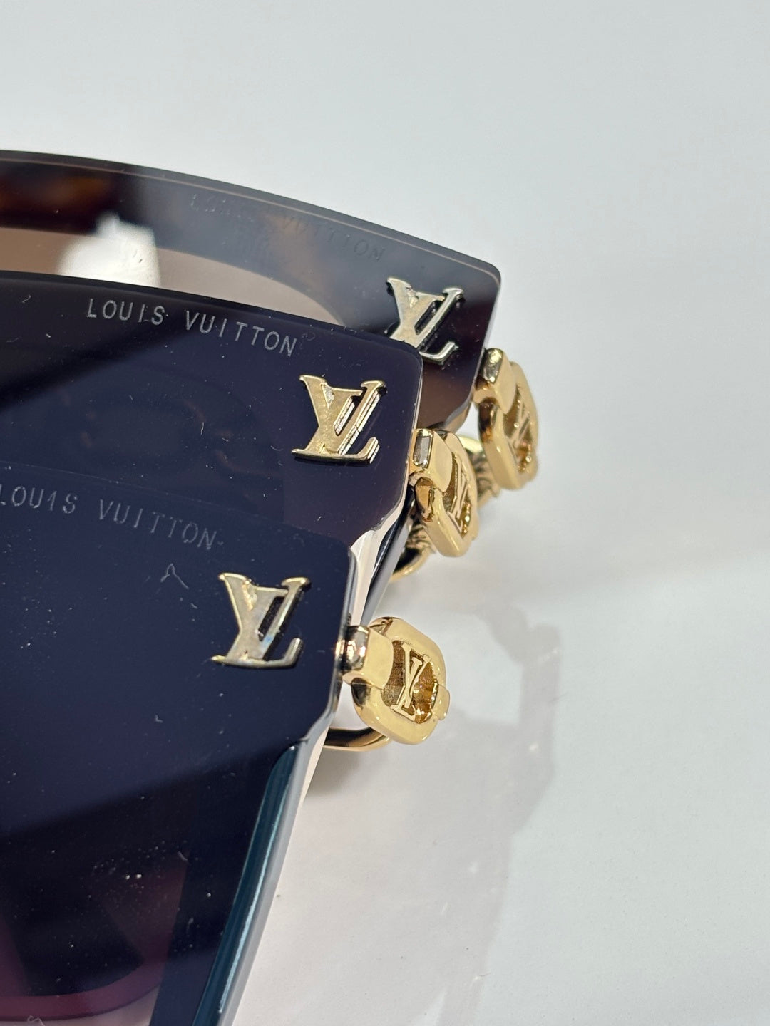 Louis Vuitton sunglasses side view with gold LV plaque on dark frame