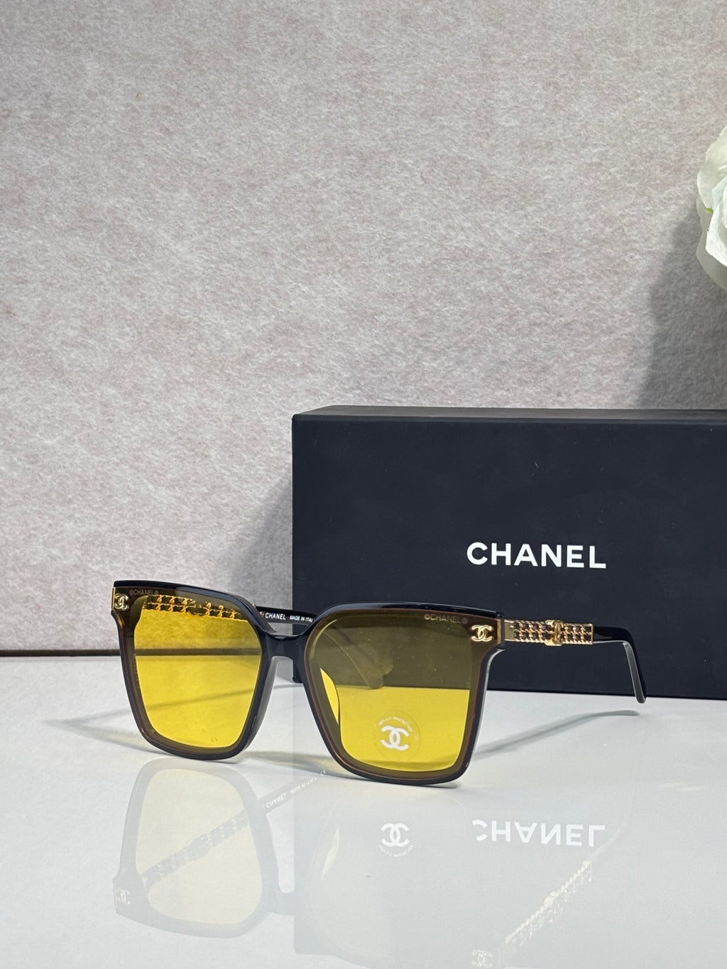 CHANEL sunglasses with dark frame and yellow-tinted lenses, gold chain temple accents