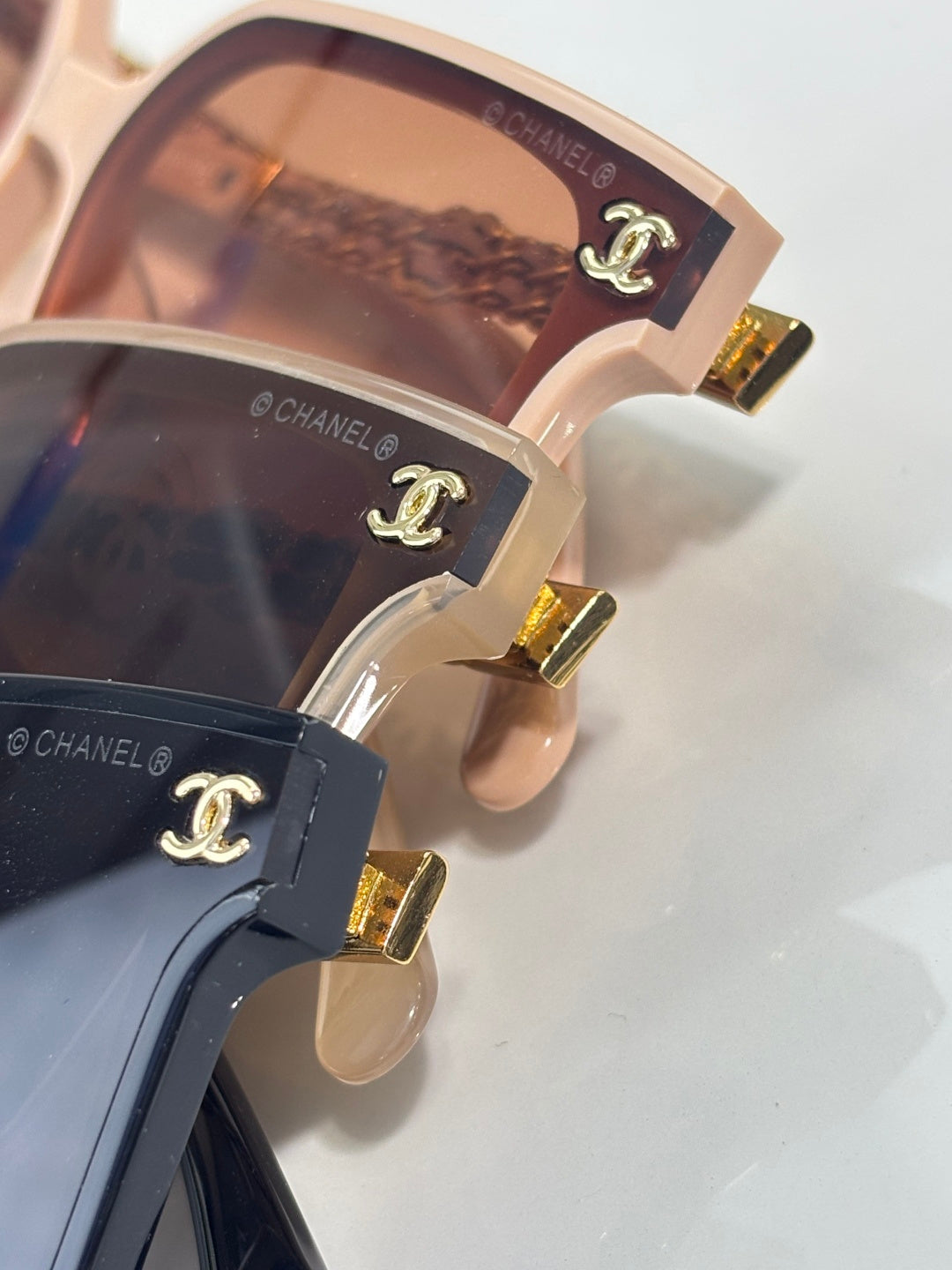 CHANEL sunglasses close-up: gold logo hinges on light and dark frames