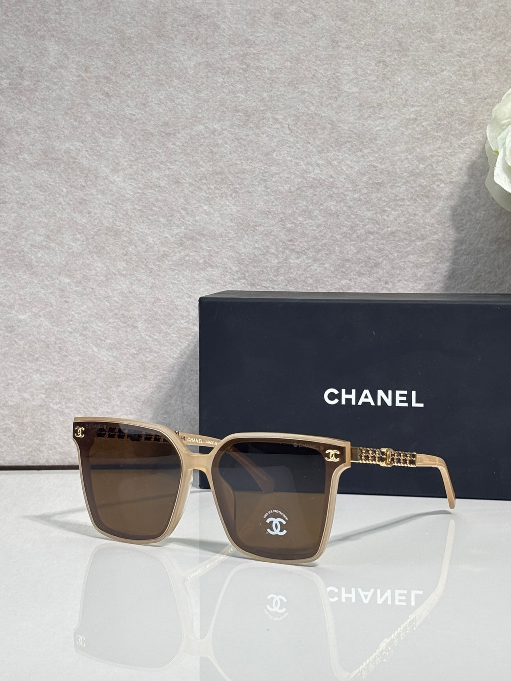 CHANEL sunglasses with light frame and brown-tinted lenses, gold chain temple details