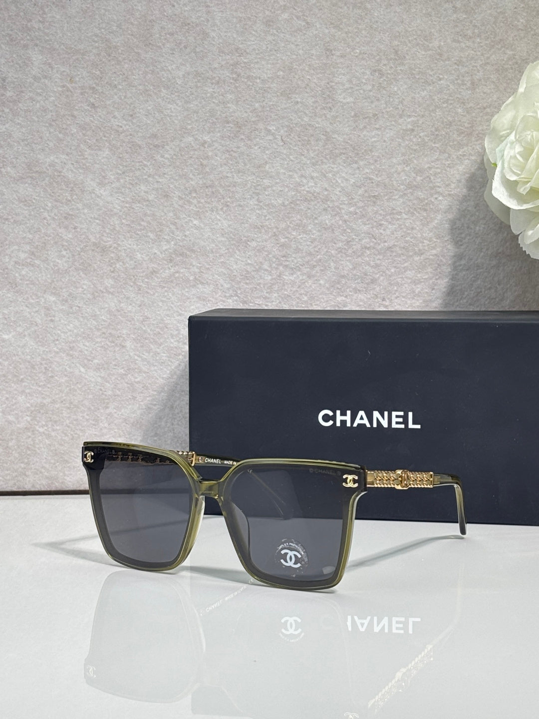 CHANEL sunglasses with olive frame and dark lenses, gold chain-style temple accents
