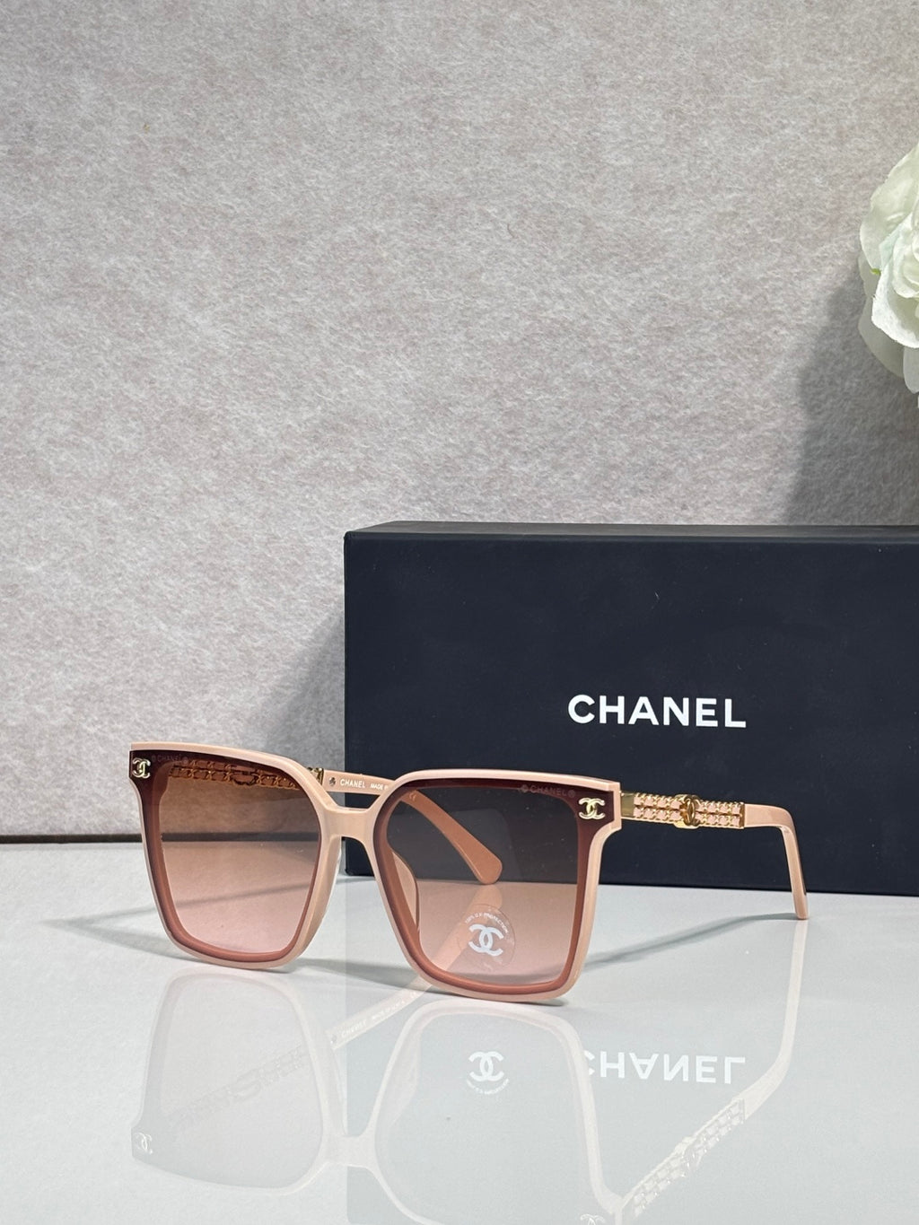 CHANEL sunglasses with pink frame and brown-tinted lenses, gold chain temple accents
