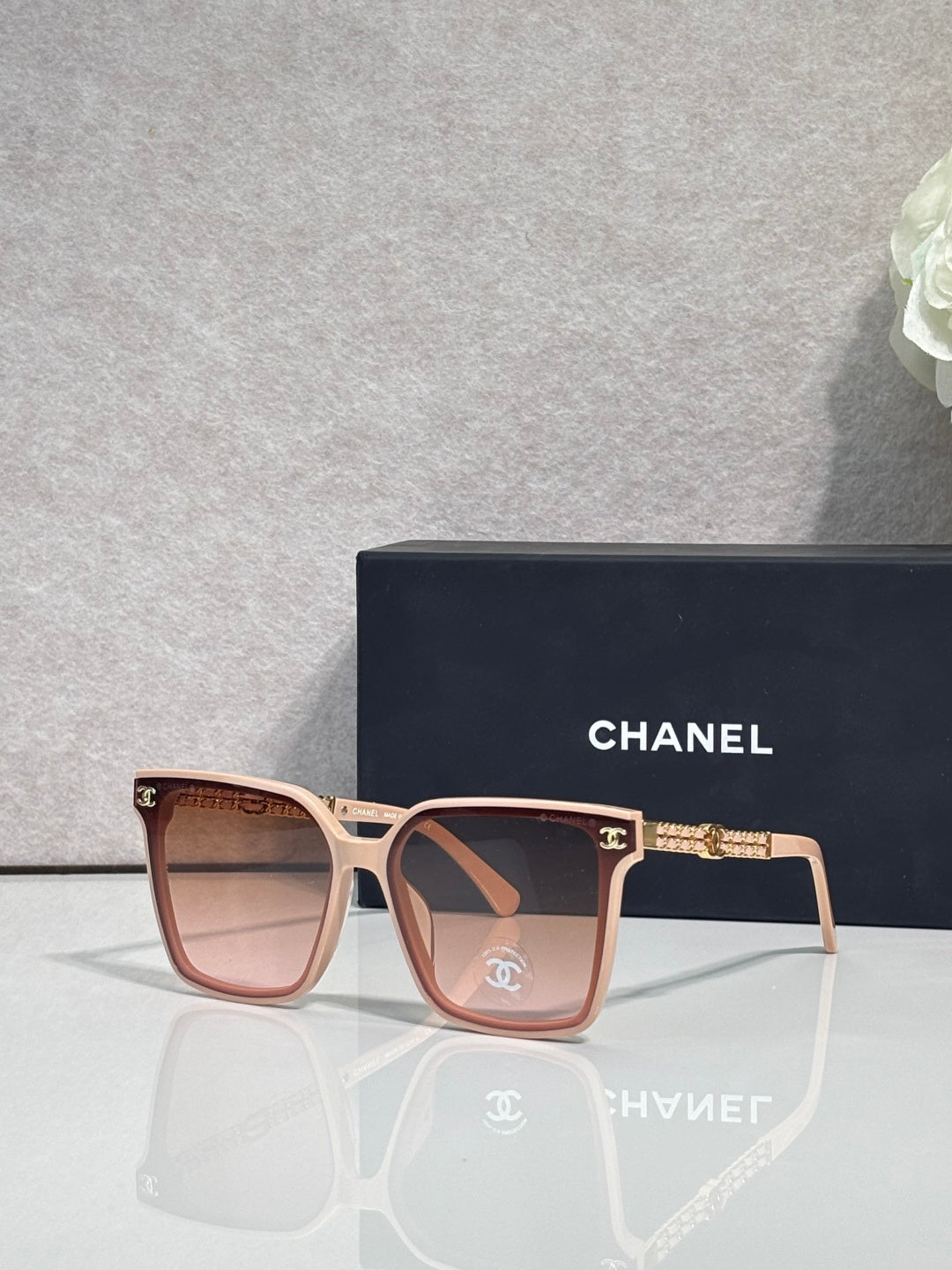 CHANEL sunglasses with pink frame and brown-tinted lenses, gold chain temple accents