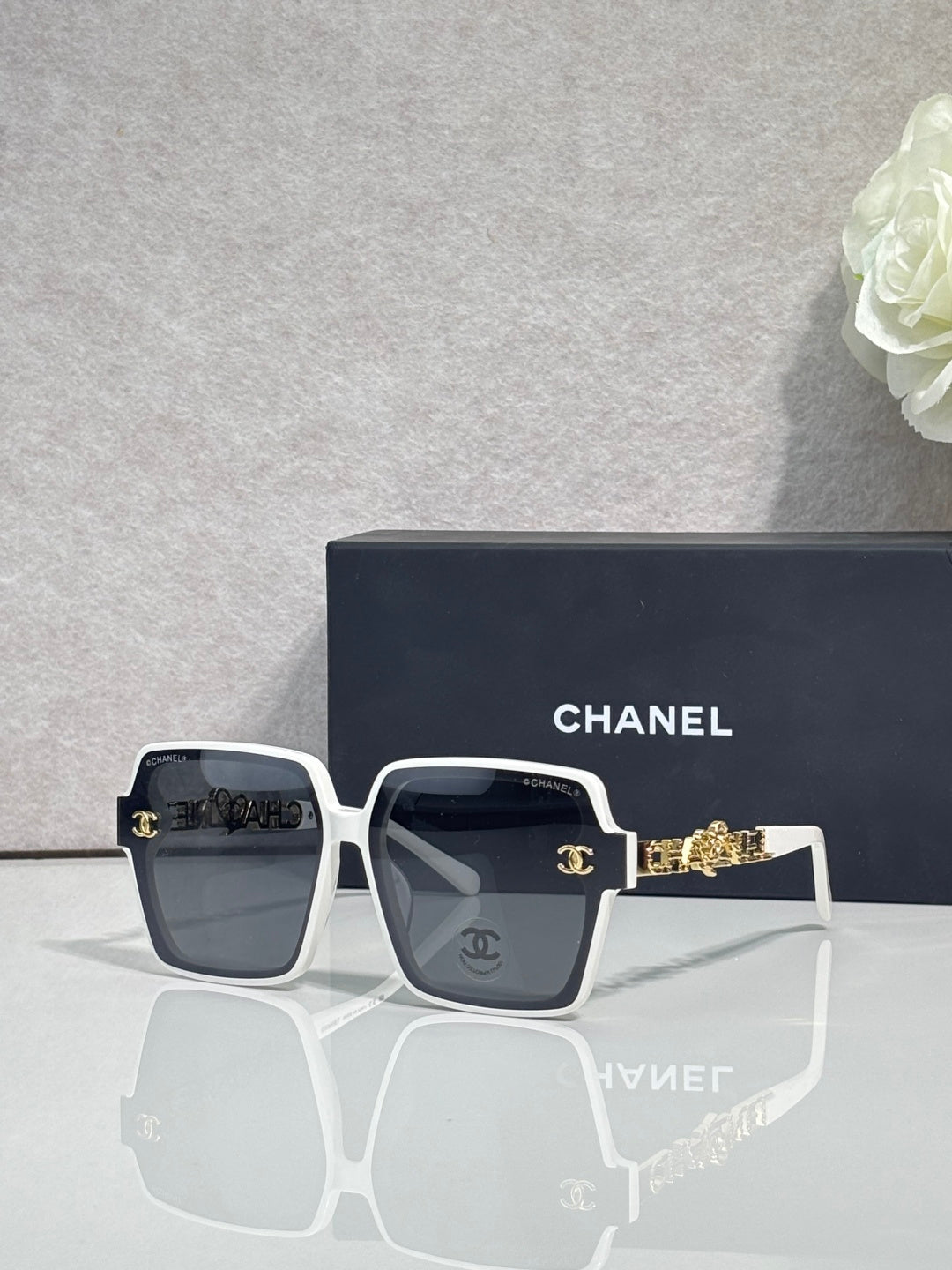 Chanel sunglasses with white square frames and gold-tone logo hardware