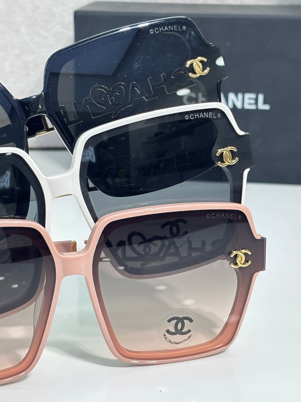 Chanel sunglasses close-up with navy, white, and pink frames and gold logos
