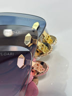 Sunglasses closeup with gold-tone hinges, dark lenses and pink accent on frame