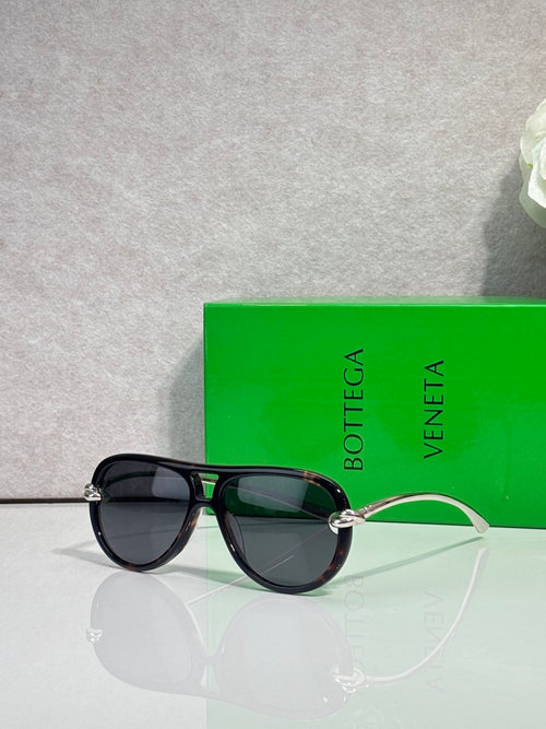 Bottega Veneta black round sunglasses with green accents and dark lenses