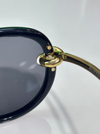 Bottega Veneta sunglasses hinge close-up with gold-tone ring on dark frame