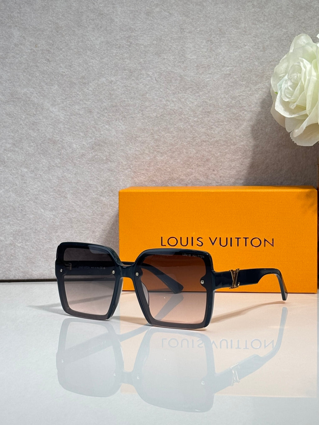 Louis Vuitton square sunglasses with dark lenses and black frame, visible logo on arms