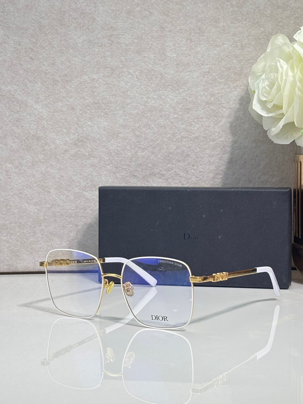 Dior eyeglasses with gold arms and blue-tinted lenses, rectangular front