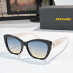 Black cat-eye sunglasses with blue gradient lenses and gold logo detail at the temple hinge
