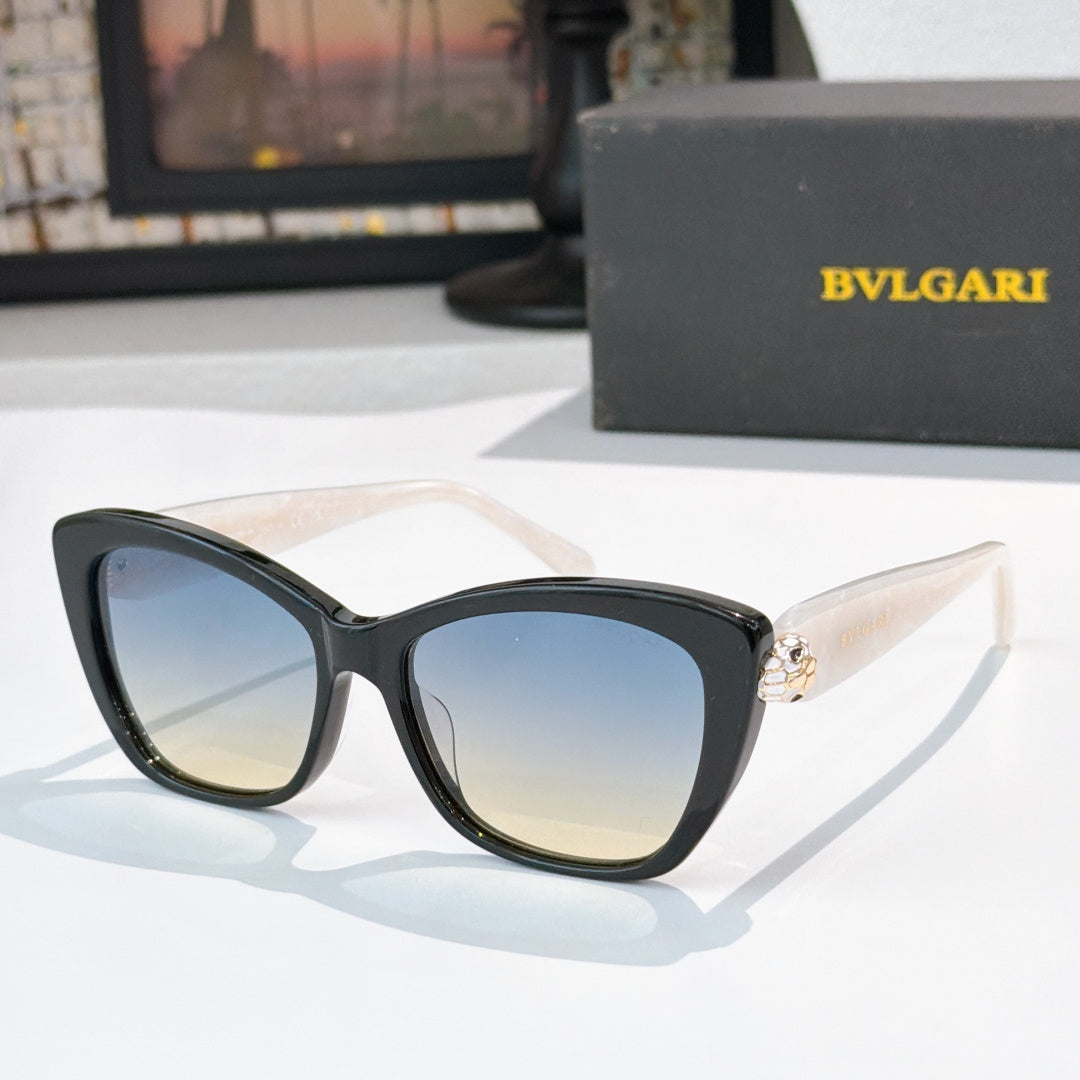 Black cat-eye sunglasses with blue gradient lenses and gold logo detail at the temple hinge