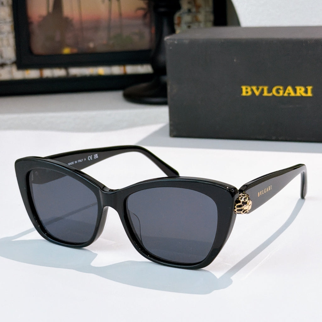 Black cat-eye sunglasses with dark blue lenses and gold logo detail at the temple hinge
