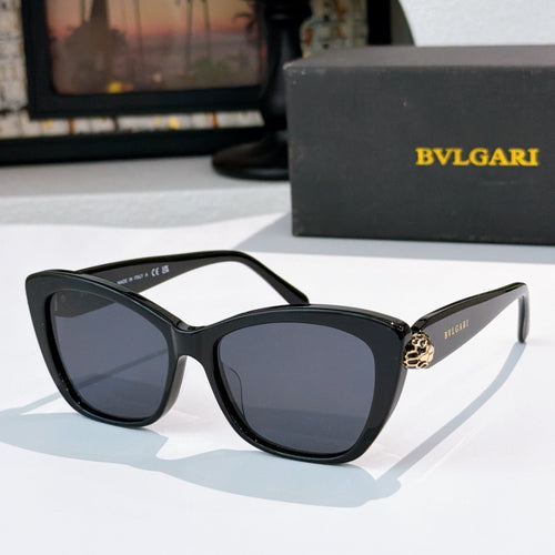 Black cat-eye sunglasses with dark blue lenses and gold logo detail at the temple hinge