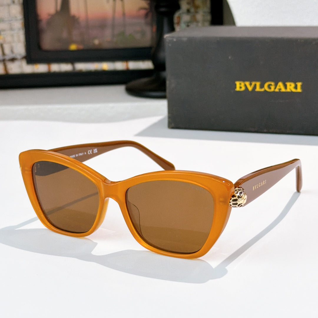 Orange cat-eye sunglasses with brown lenses and gold logo detail at the temple hinge